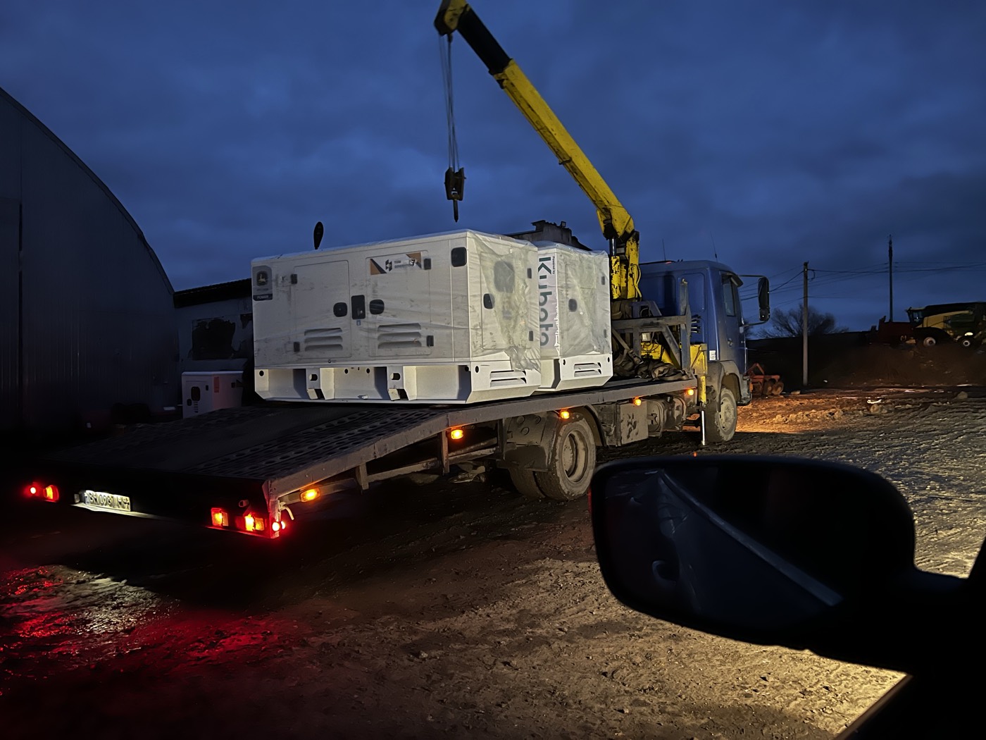 Night delivery: crane unloading a generator set after dark